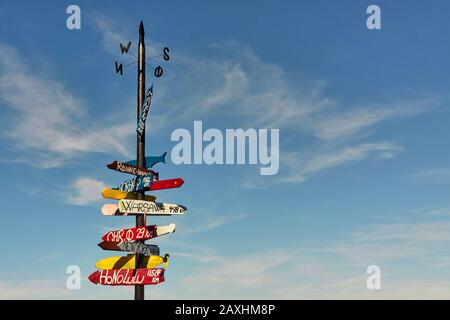 Panneau avec panneaux de signalisation colorés et distances vers différentes villes Banque D'Images