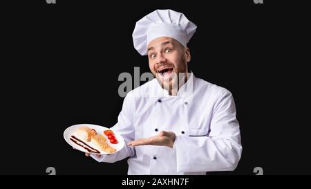 Le Chef Male Excité Sert Du Steak De Saumon À La Table Du Studio, Panorama Banque D'Images