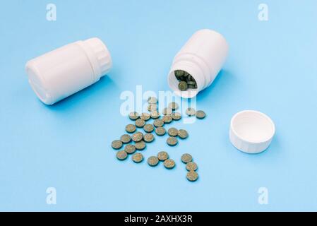 Médicaments sur fond bleu. Pilules déversées dans un pot en plastique blanc. Concept de pharmacologie de la santé Banque D'Images