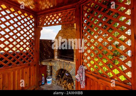 Un belvédère en bois avec un poêle à barbecue en pierre dans l'arrière-cour du cottage. Belvédère à côté de la clôture à l'angle de la cour. Il y a une pelouse verte Banque D'Images