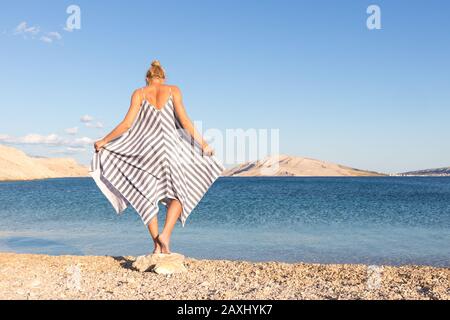 Une femme heureuse et insouciante qui se promenait en fin d'après-midi sur la plage de galets blancs sur l'île de Pag, en Croatie