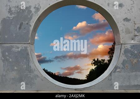 Vue sur les nuages blancs dans le ciel du coucher du soleil à travers le trou dans le mur de béton. Banque D'Images