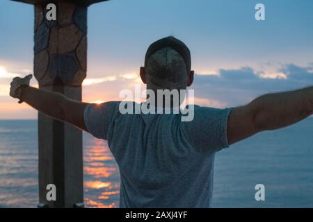Homme qui ouvre ses bras à la vue sur la mer et trouve la paix. Concept De Liberté.