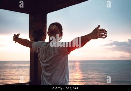Homme qui ouvre ses bras à la vue sur la mer et trouve la paix. Concept De Liberté.