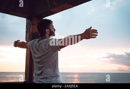 Homme qui ouvre ses bras à la vue sur la mer et trouve la paix. Concept De Liberté.