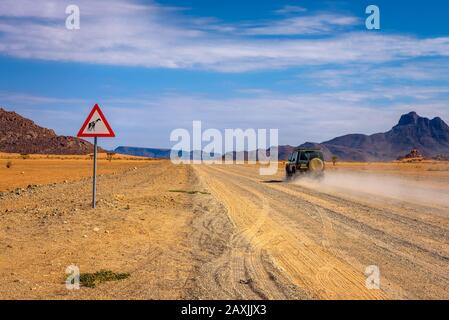 Voiture passant un panneau de signalisation Girafes dans le désert de Namibie Banque D'Images