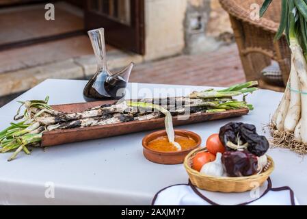 Oignons de calcottes rôtis servis sur plaque avec sauce Romesco – plat d'hiver catalan traditionnel. Banque D'Images