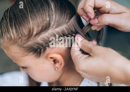 Mère fait braid de cheveux à sa fille, gros plan photo. Banque D'Images