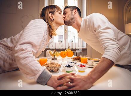 Bonjour ! Beau couple dans le baiser d'amour et prendre le petit déjeuner à la maison manger et boire de la nourriture saine. Banque D'Images