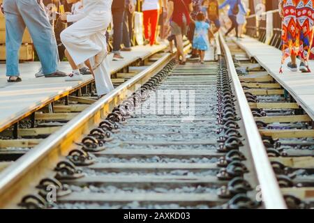 Les touristes à pied à travers l'ensemble de rail de chemin de fer d'un côté à l'autre côté tout en se rendant sur le pont de la rivière Kwai à Kanchanaburi, Thaïlande. Banque D'Images