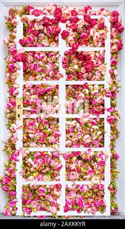 Porte de collage créative en été. Magnifique toile de fond de pivoines roses artificielles avec porte classique blanche. Fond rose floral. Fleurs roses Banque D'Images