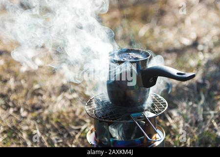 préparation du café dans les montagnes. vue rapprochée de la cafetière turque sur le brûleur portable en bois avec fumée Banque D'Images