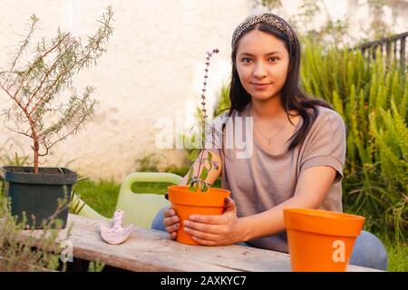 Femme hispanique souriant avec une plante de basilic potée dans les mains Banque D'Images