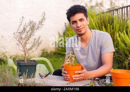 Homme hispanique souriant avec une plante de basilic potée dans les mains Banque D'Images