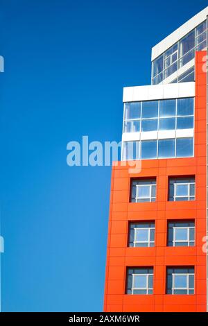 façade d'un bâtiment moderne dans le style d'un mur rouge de haute technologie, fenêtres carrées sur une journée ensoleillée avec ciel bleu clair. Espace pour le texte Banque D'Images