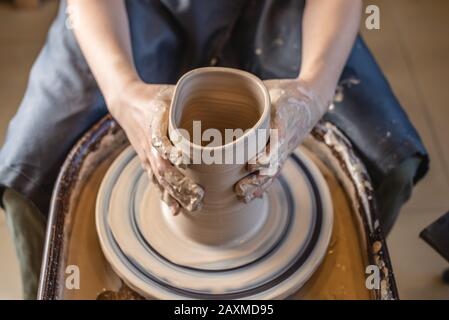 Femme potter travaillant sur une roue de Potter faisant un vase. Maître formant l'argile avec ses mains créant la verseuse dans un atelier. Gros plan Banque D'Images