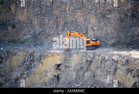 creuseur orange travaillant dans la carrière de granit Banque D'Images