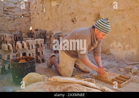 Tozeur, TUNISIE - 20 DÉCEMBRE 2019: Un travailleur local qui fabrique des briques de façon traditionnelle dans une usine de briques. Un cadre en bois est utilisé pour mouler les briques. Banque D'Images