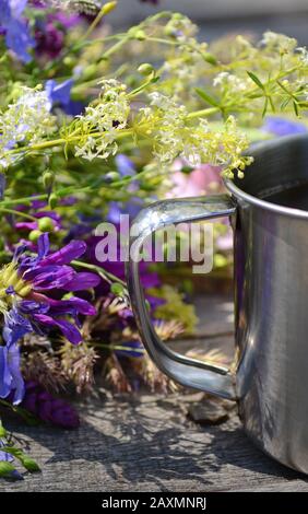 mugs touristiques à poignée métallique avec fleurs violettes et blanches sur table en bois Banque D'Images