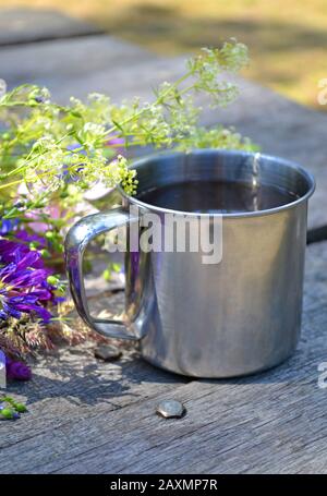 tasse en métal pour une randonnée sur la table à côté de fleurs violettes Banque D'Images