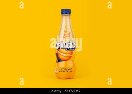 Une bouteille d'Orangina a tourné sur un fond jaune. Banque D'Images