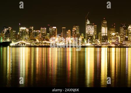 Metropolis Et Gratte-Ciel Illuminés Par Vive Lumière, À Proximité Du Grand Corps De L'Eau Contre Le Ciel Clair De Nuit Banque D'Images