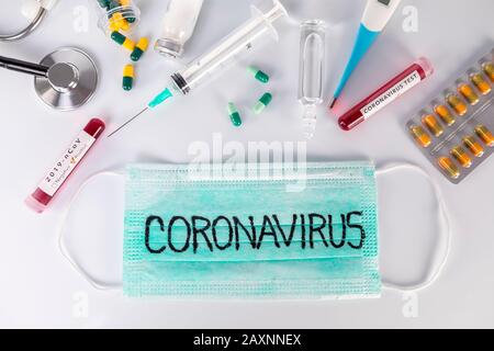 Masque médical de protection avec texte de Coronavirus et thermomètre et pilules pour stéthoscope d'ampoules médicales. Test de virus et recherche pour le concept de traitement. Banque D'Images