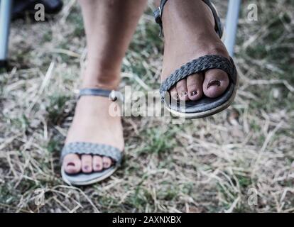 Gros plan des pieds avec clous peints dans les sandales sous le lumière du soleil avec un arrière-plan flou Banque D'Images