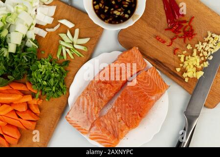 Saumon frais avec W ingrédients pour la cuisson - légumes frais et épices sur blanc. Produits sains à faible teneur en glucides. Concept de régime cétogène. Vue de dessus. Banque D'Images