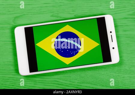 Drapeau du Brésil composé en plaçant un smartphone affichant son symbole sur un fond en bois coloré Banque D'Images