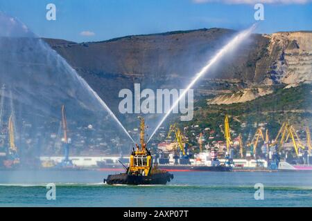 Le bateau à remorqueurs flottant est en train de vaporiser des jets d'eau, démontrant des canons à eau de lutte contre les incendies Banque D'Images