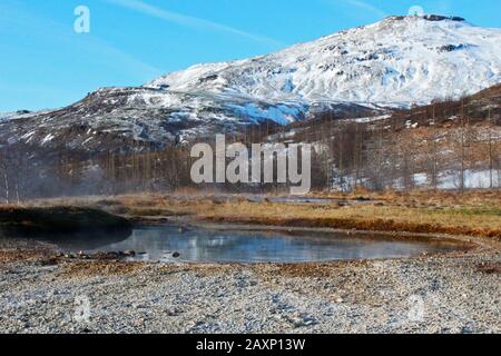 Superbe montagne enneigée et source chaude dans le parc Geysir, Islande, une journée lumineuse Banque D'Images