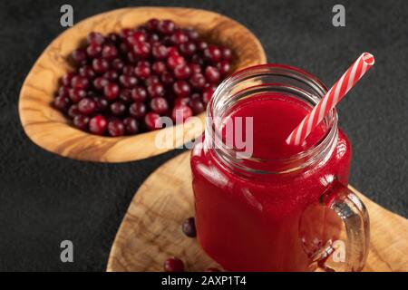 Curatif jus de canneberge dans un pot-mug en verre avec une paille sur table noire. Concept de saine alimentation Banque D'Images