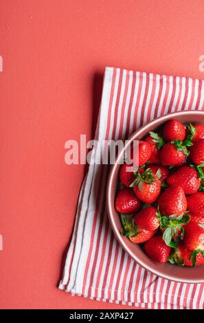 Fraises mûres, fraîchement récoltées, dans un plateau rouge sur serviette, sur une table rouge. Baies rouges sur la table de cuisine. Fruits d'été. Fruits de fraises sucrés. Banque D'Images
