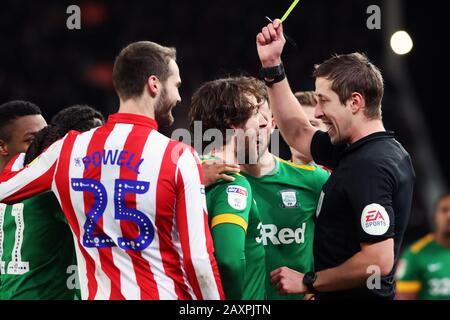 L'arbitre John Brooks montre Ben Pearson de Preston North End une carte jaune après s'être accroché à James McClean de Stoke City (non illustré) lors du match du championnat Sky Bet au stade de Stoke. Banque D'Images