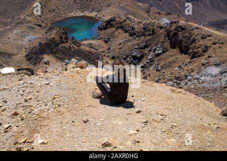 Un randonneur mâle s'est assis, regardant la vue sur les lacs émeraude, Tongariro Banque D'Images