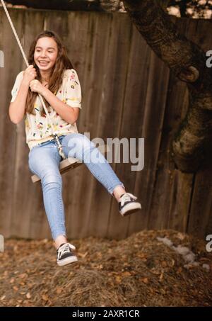 Teenage girl on rope swing en arrière-cour. Banque D'Images