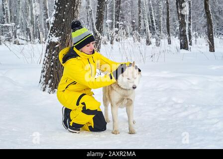 la jeune femme communique avec un chien husky dans la forêt hivernale Banque D'Images