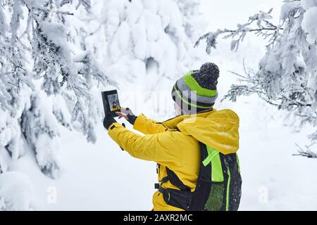 femme voyageur avec un sac à dos dans une forêt hivernale enneigée fait selfie Banque D'Images