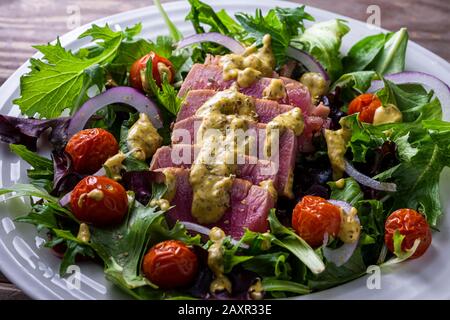 Bifteck de thon grillé en tranches sur les salades vertes. Banque D'Images