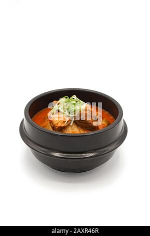 Soupe Kimchi isolée dans le bol en pierre noire en studio lumière sur le fond blanc. Banque D'Images