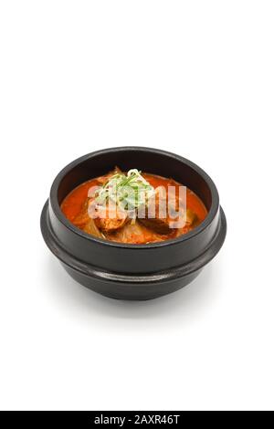 Soupe Kimchi isolée dans le bol en pierre noire en studio lumière sur le fond blanc. Banque D'Images