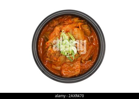 Soupe Kimchi isolée dans le bol en pierre noire en studio lumière sur le fond blanc. Banque D'Images