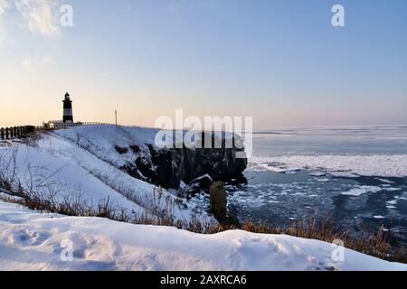 Coucher de soleil au Cap Notoro avec phare Notoromisaki en hiver, Abashiri, Hokkaido, Japon Banque D'Images