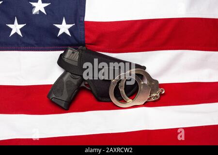 Pistolet, étui et menottes devant le drapeau américain, horizontal Banque D'Images