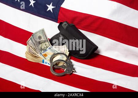 Pistolet dans l'étui, les menottes et l'argent devant le drapeau américain, horizontal Banque D'Images