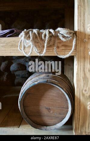 Un tonneau à vin, une corde épaisse et un tissu violet sur une étagère contre le mur de pierre dans la réserve du château. Banque D'Images