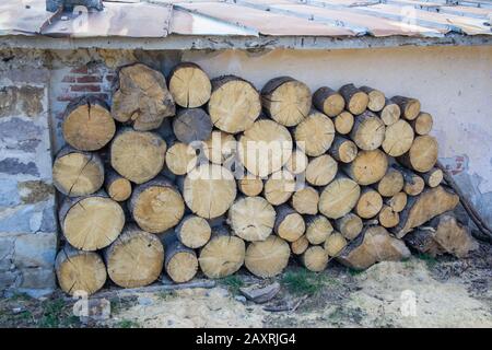 Pile de grands bois ronds devant une maison. Grumes, carburant pour chauffage. Bois de chauffage empilé. Fond en bois naturel Banque D'Images