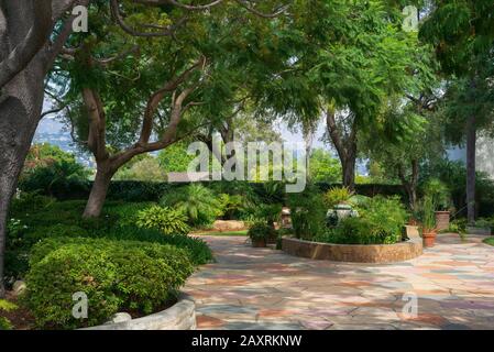 La cour californienne avec patio en pierre, plantes luxuriantes et un auvent confortable créé par une quantité saine d'arbres Banque D'Images