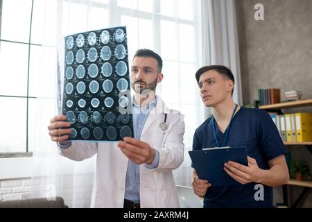 Deux jeunes médecins ont l'air sérieux lors de l'analyse des résultats d'IRM Banque D'Images